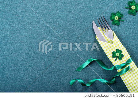 Silverware in green napkin for St Patrick day on table Silverware in green napkin for St Patrick day on table 86606191