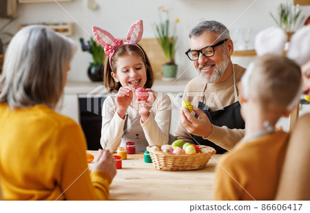 Happy family grandfather and little granddaughter holding wicker basket full of painted boiled eggs Happy family grandfather and little granddaughter holding wicker basket full of painted boiled eggs 86606417