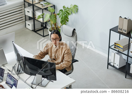 Young serious male diversity programmer looking attentively at computer screen Young serious male diversity programmer looking attentively at computer screen 86608216