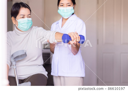 Physiotherapist training with elderly woman patient using dumbbell in hospital,Physical therapy concept 86610197