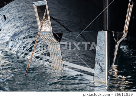 The mesmerizing reflection of the water on the glossy side of a huge yacht anchored, chrome details, chains and ropes to the muring descend into the water The mesmerizing reflection of the water on the glossy side of a huge yacht anchored, chrome details, chains and ropes to the muring descend into the water 86611839