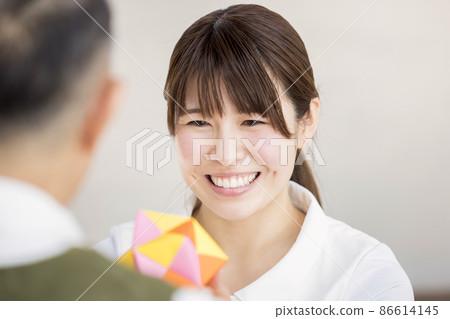 Long-term care image: A caregiver female who is pleased to receive an origami Kusudama 86614145