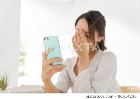 Female in her 30s looking at a smartphone, housewife 86614236