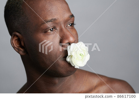 African man posing with white flower 86617100