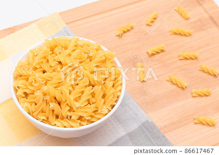 Uncooked Fusilli Pasta in White Bowl on Wooden Board Uncooked Fusilli Pasta in White Bowl on Wooden Board 86617467