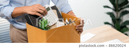 Resignation Concept The man in light blue shirt standing at the desk and putting the calculator and other stuff into the box 86620024