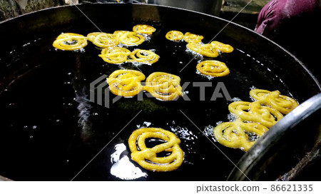 Indian jalebi frying in oil pan at stall 86621335