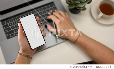Female officer working on laptop computer and holding a smartphone mockup. Female officer working on laptop computer and holding a smartphone mockup. 86622741