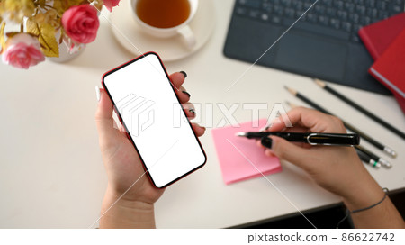 A female hand holding a smartphone blank screen A female hand holding a smartphone blank screen 86622742