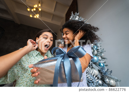 Two young and happy best friends a roommates exchange gifts. Two young and happy best friends a roommates exchange gifts. 86622776