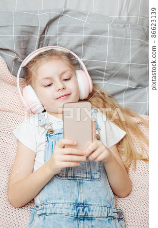 Little girl with mobile phone listening to music Little girl with mobile phone listening to music 86623139