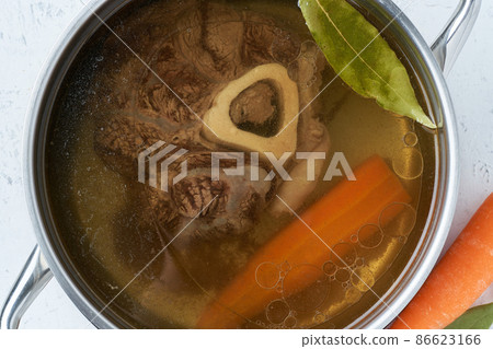 Beef meat broth, ossobuco on bone, rich soup in saucepan, long slow languishing cooking. Beef meat broth, ossobuco on bone, rich soup in saucepan, long slow languishing cooking. 86623166