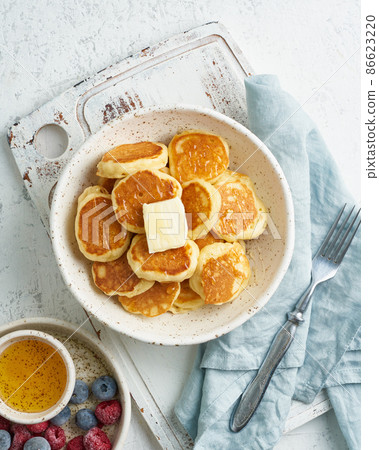 Pancakes cereal, tiny thin funny crumpet, children's food. Breakfast with drink, white table Pancakes cereal, tiny thin funny crumpet, children's food. Breakfast with drink, white table 86623220