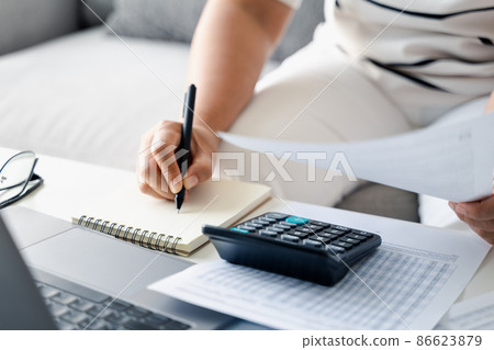 Woman is calculating annual tax, monthly expenses with calculator and filling form of Individual Income Tax Return. Season to pay Tax and Budget planning concept. 86623879