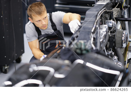 Concentrated serious handyman with tool fix damaged motorbike in garage Concentrated serious handyman with tool fix damaged motorbike in garage 86624265