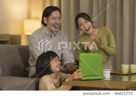 Family tablet PC spending time in the living room at night 86625755