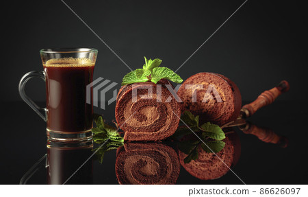 Chocolate cake with mint and a mug of black coffee. Chocolate cake with mint and a mug of black coffee. 86626097