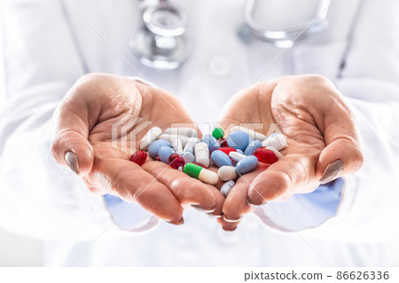 Detail of a doctor holding handfull of various colorful pills in both hands Detail of a doctor holding handfull of various colorful pills in both hands 86626336