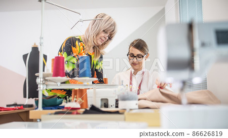 Two generations of female tailors cooperate at work in the small workshop Two generations of female tailors cooperate at work in the small workshop 86626819
