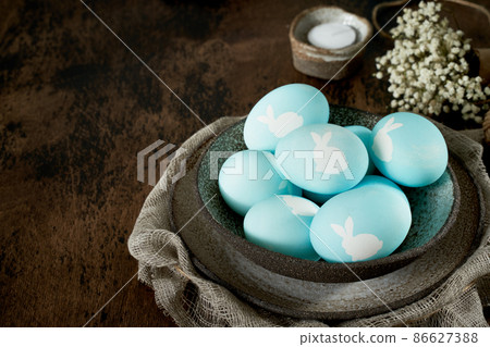 Unusual Easter on dark old background. Ceramic brown bowl with blue eggs. Unusual Easter on dark old background. Ceramic brown bowl with blue eggs. 86627388