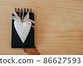 notebook with black sheets on a wooden table with a white heart. 86627593