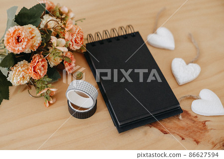 notebook with black sheets with copy space, bouquet of flowers and a white heart. 86627594