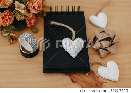notebook with black sheets with copy space, bouquet of flowers and a white heart. notebook with black sheets with copy space, bouquet of flowers and a white heart. 86627595