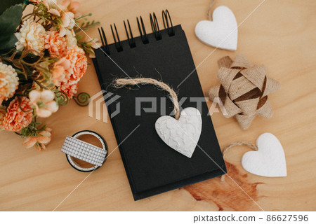 notebook with black sheets with copy space, bouquet of flowers and a white heart. 86627596