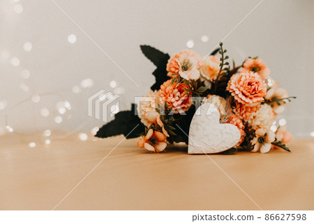 wooden table with a bouquet of flowers and a white heart 86627598