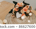 wooden table with a bouquet of flowers and a white heart 86627600