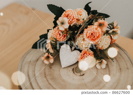 wooden table with a bouquet of flowers and a white heart wooden table with a bouquet of flowers and a white heart 86627600