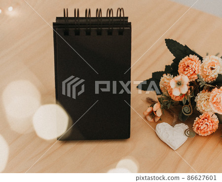 notebook with black sheets with copy space, a bouquet of flowers and a white heart 86627601