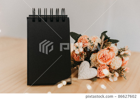 notebook with black sheets with copy space, bouquet of flowers and a white heart. notebook with black sheets with copy space, bouquet of flowers and a white heart. 86627602
