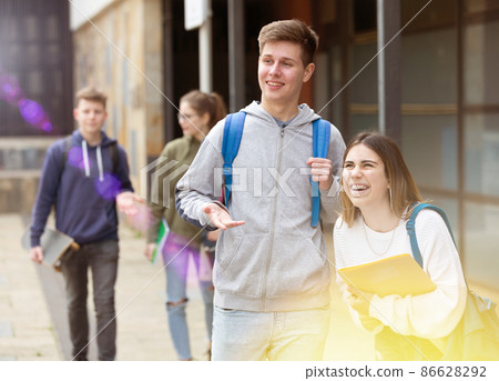 Carefree teen students boy and girl friendly talking Carefree teen students boy and girl friendly talking 86628292
