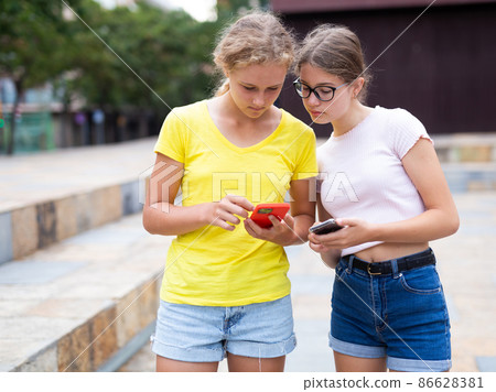 Two teenagers chatting on their smartphone 86628381
