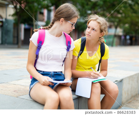 Two classmates on the street at a big break in the middle of the day waiting for start of classes 86628383