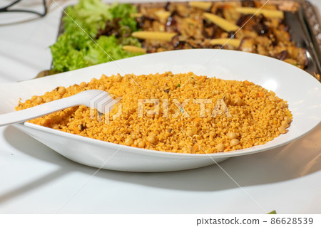Easy bulgur pilaf pilavi with tomatoes in a ceramic bowl on a dark background close-up. Turkish cuisine, vegan food. 86628539