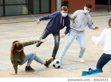 teenagers in protective face masks are playing football 86628541