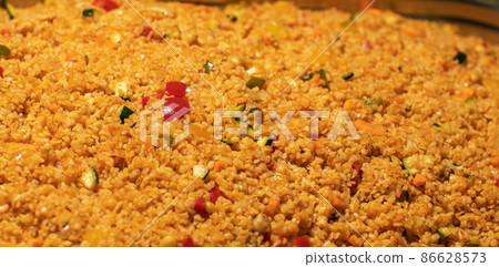Easy bulgur pilaf pilavi with tomatoes in a ceramic bowl on a dark background close-up. Turkish cuisine, vegan food. Easy bulgur pilaf pilavi with tomatoes in a ceramic bowl on a dark background close-up. Turkish cuisine, vegan food. 86628573