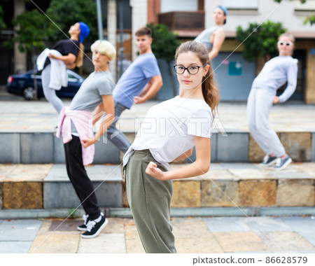 Portrait of emotional girl doing hip hop movements during group class at street Portrait of emotional girl doing hip hop movements during group class at street 86628579