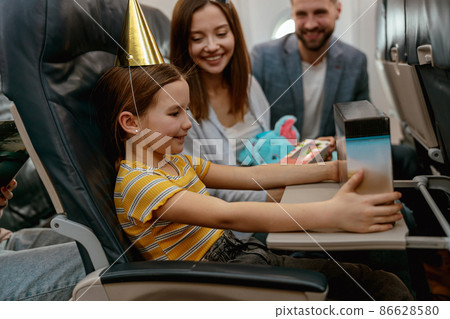 Little girl celebrating birthday with parents in airplane Little girl celebrating birthday with parents in airplane 86628580