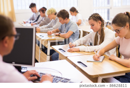 Teenage students studying in classroom with teacher Teenage students studying in classroom with teacher 86628811