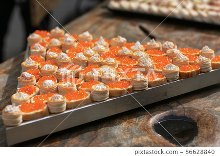 tartlets with butter and red caviar on a black wooden table 86628840