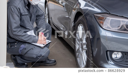 A man in work clothes checking a car A man in work clothes checking a car 86628929