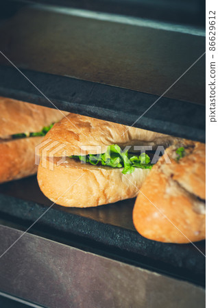 Sandwiches in the making. Fresh buns with filling on the plancha grill. Sandwiches in the making. Fresh buns with filling on the plancha grill. 86629612