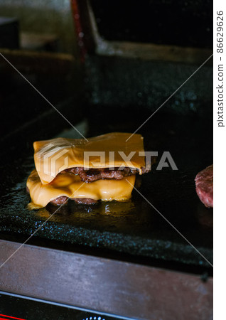 Double beef burgers with cheese on a plancha grill. Food preparing concept. 86629626
