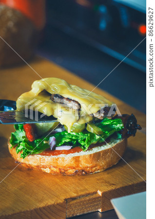 Double cheeseburger in the making. Fresh letucce leaf, beefm cheese and sauces. 86629627