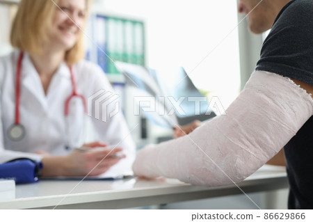 Male patient with bandage on his arm sitting at traumatologist appointment closeup Male patient with bandage on his arm sitting at traumatologist appointment closeup 86629866
