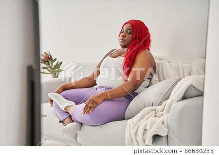 Concentrated young woman meditating at home in the morning and practicing yoga while sitting Concentrated young woman meditating at home in the morning and practicing yoga while sitting 86630235