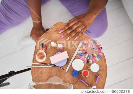 Young multiracial woman applying colored nail polish at the table at home at the self isolation 86630278